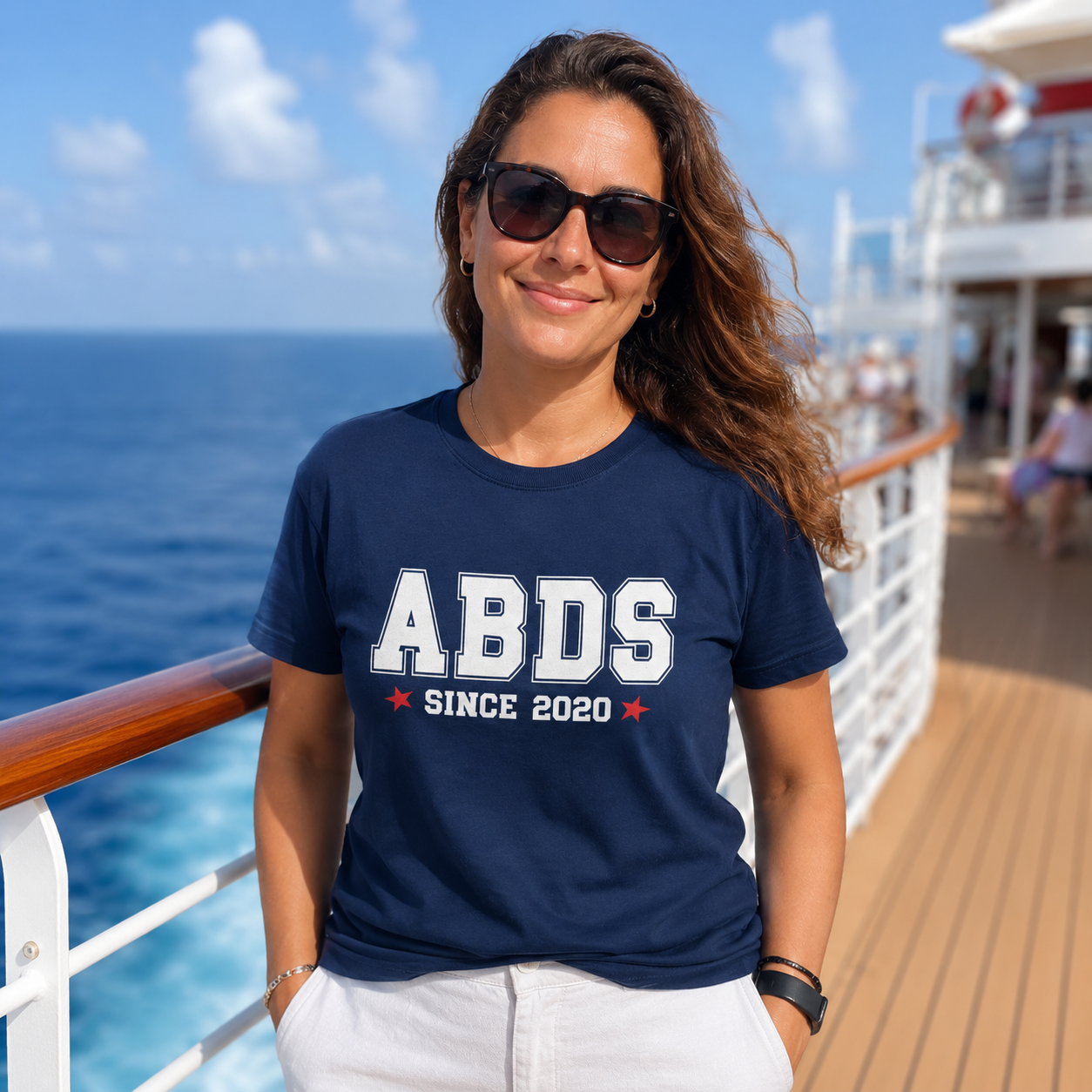 Woman wearing a navy blue t-shirt with 'ABDS Since 2020' on a cruise ship deck.