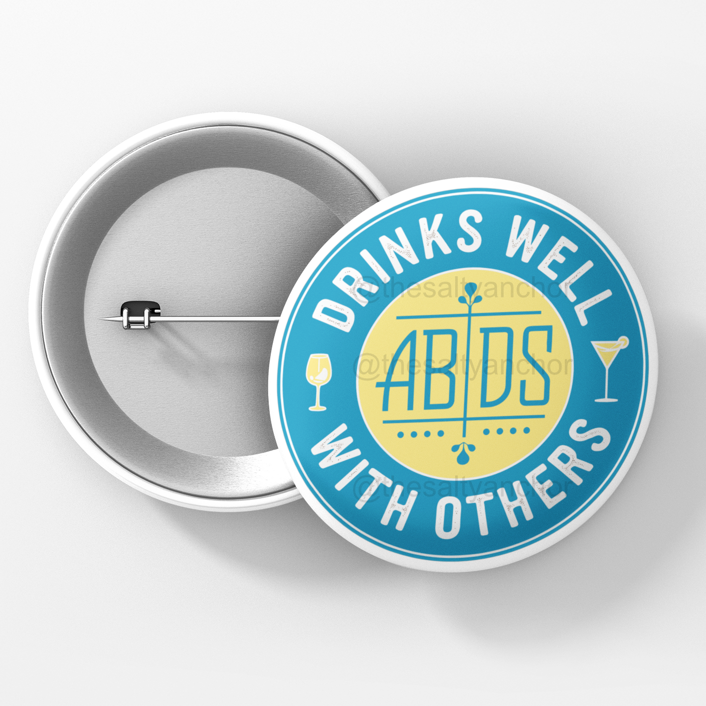 A round pin with a blue background and a yellow center, featuring the text 'ABDS DRINKS WELL WITH OTHERS' and illustrations of drinks.