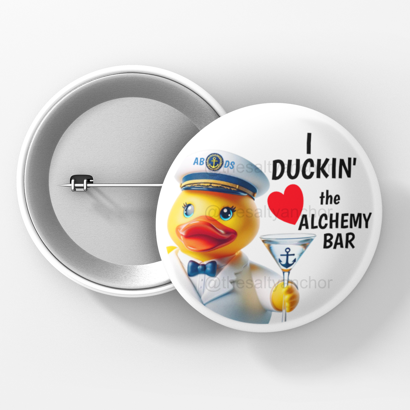 A button pin with an illustration of a yellow rubber duck dressed as a captain, holding a martini glass, with text 'I DUCKIN' the AlCHEMY BAR' on a white background.