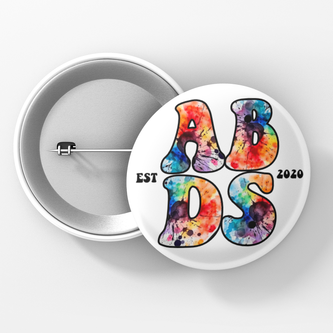 Button badge with tie-dye text 'ABDS' and 'EST 2020' on a white background
