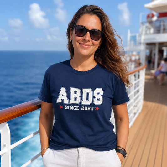 Woman wearing a navy blue t-shirt with 'ABDS Since 2020' on a cruise ship deck.