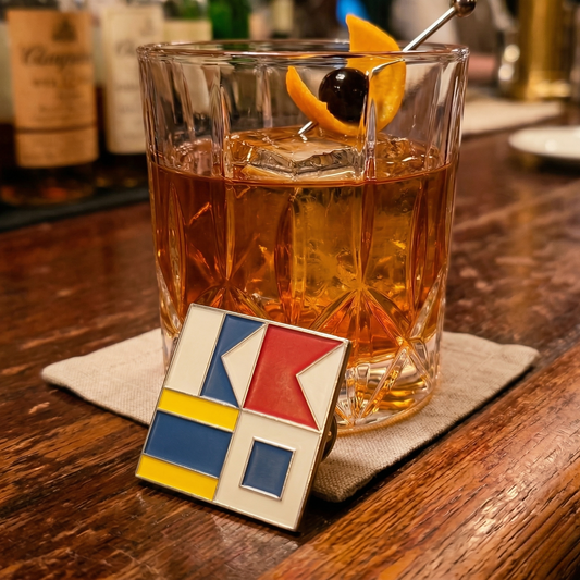 Glass of whiskey with an orange slice and cherry on a wooden bar, featuring a geometric pendant.