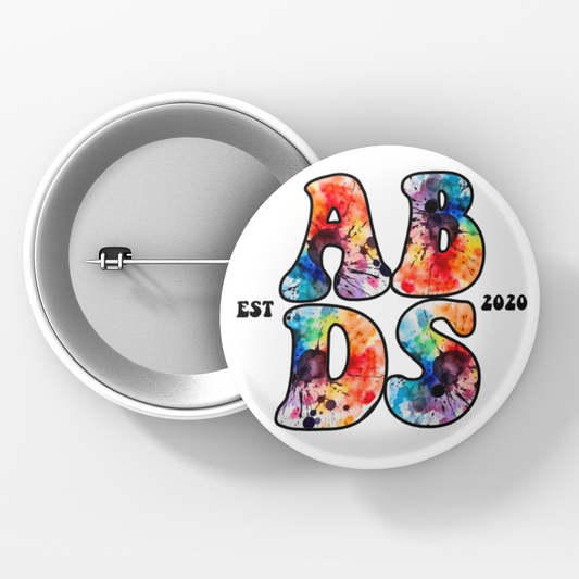 Button badge with tie-dye text 'ABDS' and 'EST 2020' on a white background